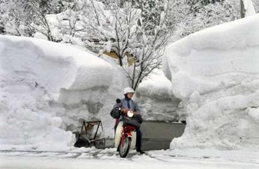 A postman riding a motorcycle delivers through heavy snow in the northern Japanese town of Tsunan January 6, 2006.