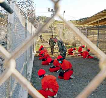 Detainees sit in a holding area watched by military police at Camp X-Ray inside Naval Base Guantanamo Bay, Cuba, during their processing into the temporary detention facility in this January 11, 2002 file photo.