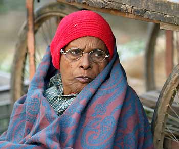 A homeless Indian woman wraps herself in a blanket as she sits on a street in New Delhi January 8, 2006. 