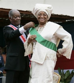 Liberia's new President Ellen Johnson Sirleaf, right, is helped with a sash by Liberian Senior Ambassador-at-large George W. Wallace, Jr., during her inauguration at the Capitol Building in Monrovia, Liberia, Monday, Jan. 16, 2006.