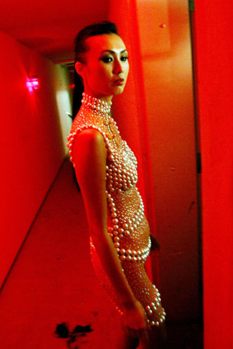 A model wearing body makeup with pearls and sequins in the style of the Chinese Qi Pao dress prepares before a Chinese New Year celebration MAC fashion show in New York February 2, 2006.