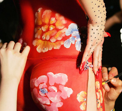 Makeup artists apply details to a model wearing body paint in the style of the Chinese Qi Pao dress before the MAC fashion show in New York February 2, 2006. 