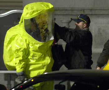 A worker in hazardous materials gear (L) prepares to enter the Russell Senate Office Building in Washington February 8, 2006. A sensor in the building had detected a possible nerve agent and HAZMAT teams were dispatched to test the substance.