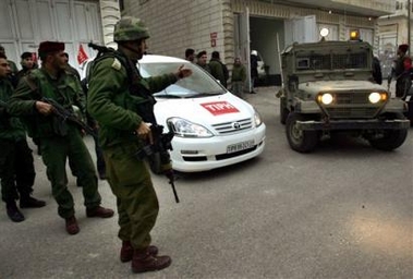 Israeli Army officers and Palestinian policemen, stand as members of the TIPH, Temporary International Presence in Hebron, leave the West Bank city of Hebron Wednesday, Feb. 8, 2006.