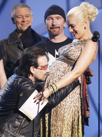 Bono of music group U2 kisses the stomach of Gwen Stefani, who is pregnant with her first child, onstage at the 48th annual Grammy Awards in Los Angeles February 8, 2006.