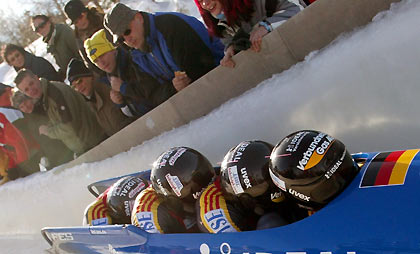 Spectators watch as Germany 1 with pilot Matthias Hoepfner, Marc Kuehne, Ronny Listner and brake man Andreas Barucha (R-L) speed down the track during their first run at the FIBT Bobsleigh World Cup four men competition in the eastern German town of Altenberg January 29, 2006.