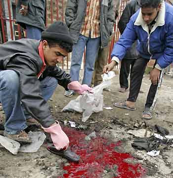 Iraqis collect belongings of victims at the scene of a suicide bomb attack outside a bank in Baghdad February 13, 2006. Some seven people were killed and 47 wounded in Baghdad on Monday when a suicide bomber detonated his explosive belt as people queued up outside a bank, a police source said. The source said poor Iraqis were queuing up to collect compensation for food rations the government had failed to distribute last year, when the explosion scattered bloodied bodies into the street in an eastern district of the capital.