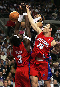 Detroit Pistons guard Ben Wallace (L) and guard Carlos Delfino (R) pressure New Jersey Nets guard Vince Carter (C) during the second half of their NBA game in Auburn Hills, Michigan February 14, 2006. Detroit defeated New Jersey 85-71. 