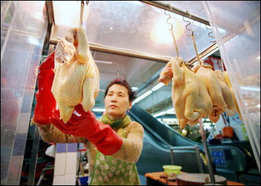A poultry vendor weights sells cooked chickens at a market in Hong Kong, 06 March 2006. Hong Kong has stepped up checks at markets and poultry farms, and the government enforced a ban on bird and poultry import from Southern China after the death of a man from bird flu in nearby Guangdong province.(AFP