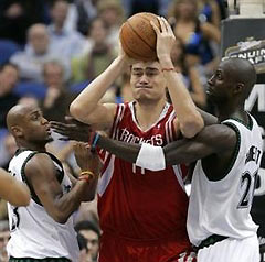 looks to pass to a teammate while under pressure from Minnesota Timberwolves forwards Kevin Garnett, right, and Trenton Hassell, left, during the fourth quarter of an NBA basketball game in Minneapolis, Tuesday, March 7, 2006. Yao had a game-high 30 points as the Rockets beat the Timberwolves 93-87.