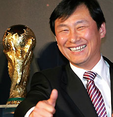Nan Yong, vice president of the China Football Association, poses next to the FIFA World Cup trophy on display in Beijing March 14, 2006. The trophy is on its inaugural journey to 31 cities in 29 countries ahead of the 2006 World Cup which begins June 9 in Germany. 
