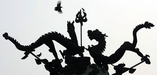 A bird flies past dragon sculptures at a park where activities are held to mark a two-year-countdown to the 2008 Olympic Games in Beijing, August 8, 2006.