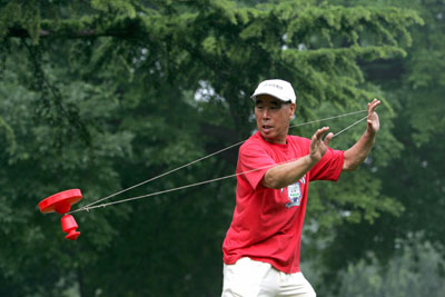 An elderly man spins a top to showcase traditional recreational games during activities to mark a two-year-countdown to the 2008 Olympic Games in Beijing, August 8, 2006.