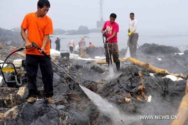 Workers clean the reefs with high-pressure guns at Xieziwan bay in Dalian, Northeast China's Liaoning Province, July 30, 2010. Reefs cleaned after Dalian oil spill