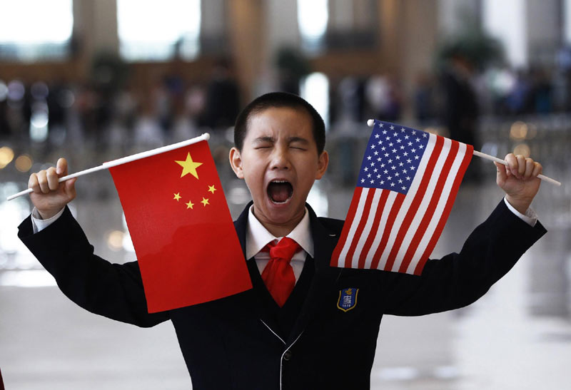 A boy who is waiting to greet US Secretary of State Hillary Clinton at the National Museum makes a face while holding the US and Chinese flags in Beijing, May 4, 2012. Reuters images of the year 2012 - Children
