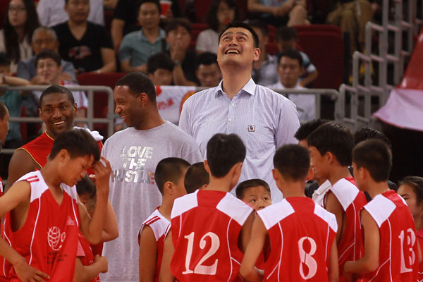 NBA star Tracy McGrady, back second left, stands beside his former Houston Rockets' teammate Yao Ming, back center, and others at a charity basketball game organized by the Yao Foundation in Beijing, July 1, 2013. Yao Ming, McGrady team up for charity
