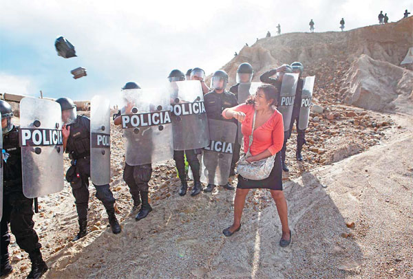 A Woman Throws A Rock And A Bag At Riot Policemen Who Block Her Way