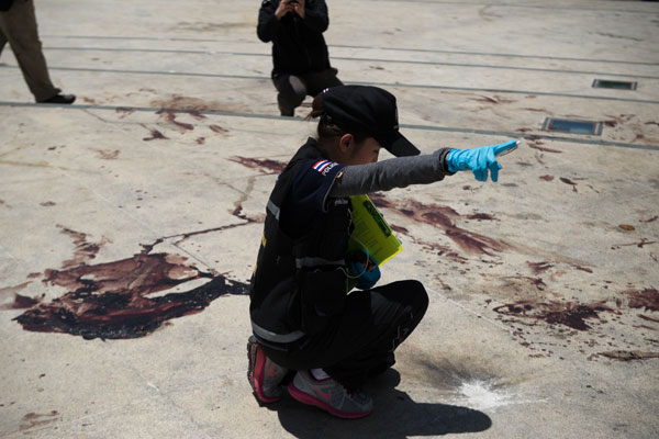 A Thai Forensic Police Officer Points In The Direction Of