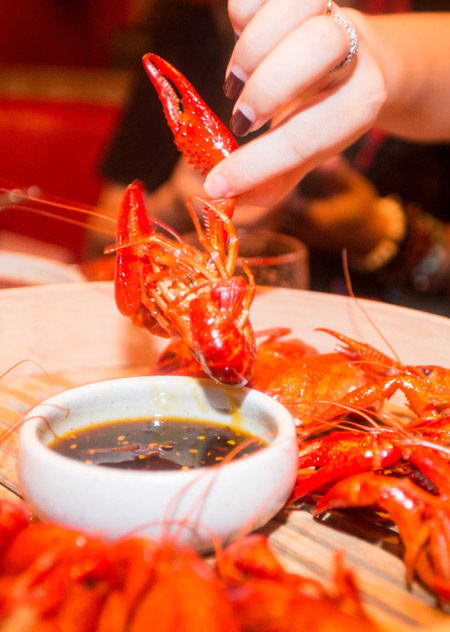 a diner enjoys a popular dish of crayfish with spicy sauce and