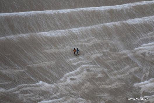 Tourists enjoy snow scenery in Dunhuang's desert