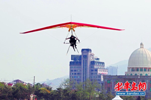 Hang gliding man flies over Jiaozhou Bay