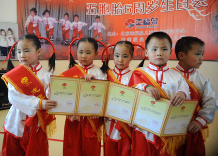 The Jiao quintuplets from Cangzhou, Hebei province, display their certificates as young ambassadors for the Beijing Olympic Games. They were granted the honor in Beijing on Tuesday to coincide with their sixth birthday. [Xinhua]