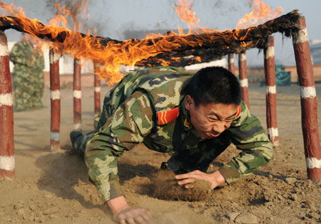 A policeman crawls under a burning mat during a training session at Qinhuangdao Frontier Inspection Station as part of security preparations for the upcoming Beijing Olympics, March 11, 2008.