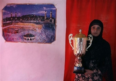 Mehbooba Ahadyar 19 , an Olympic track star posses as she holds a trophy at her home in Kabul, Afghanistan, March 11, 2008. Ahdyar is the only woman among four Afghans due to represent the war-torn country at August's Beijing Olympics and the slightly built 19-year-old 1,500 metre runner stands little chance of a medal. Competing, however, is more about pride and showing the world what Afghan women can do. Picture taken March 15, 2008. [Agencies]