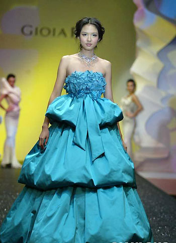 Zhang Zilin, who was crowned Miss World 2007, presents a creation by Taiwan designer Pan Yiliang in Beijing March 31, 2008. Zhang has just finished the production of a music recording for an Olympic song 'World follows me'. [Qianlong.com]