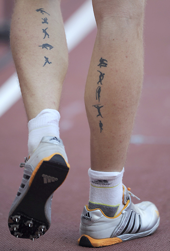 Pictogram tattoos of the disciplines of the decathlon are seen on the legs 