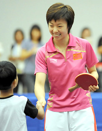 Olympic table tennis gold winner Zhang Yining shakes hands with a local child on Saturday. China&apos;s Olympic gold medallists arrived in Hong Kong on Friday, kicking off their three-day visit to the city.[Xinhua]