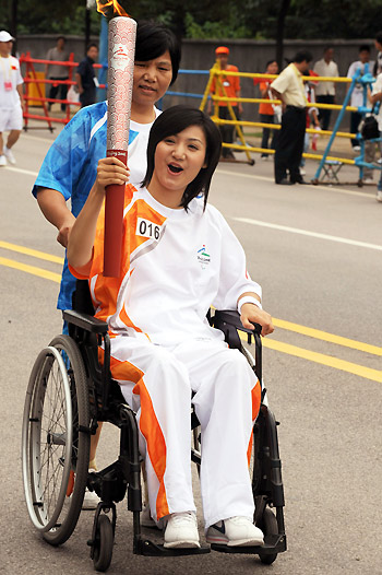 Liang Qiong, a worker in a publishing company, holds the torch during her leg of Paralympic torch relay in Changsha, Hunan province on August 31, 2008. [Xinhua] 