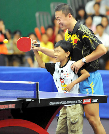 Olympic table tennis gold medallist Ma Lin gives instructions to a local child in Hong Kong, August 30, 2008. China's Olympic gold medallists arrived in Hong Kong on Friday, kicking off their three-day visit to the city. [Xinhua]