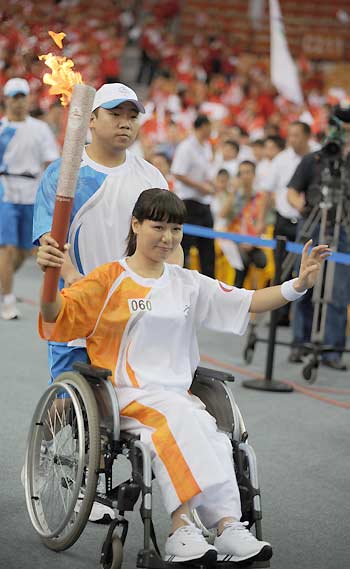 Wen Qing, a decorated wheelchair racing athlete, holds the torch during her leg of Paralympic torch relay in Wuhan, central China's Hubei province August 31,2008. [Xinhua]