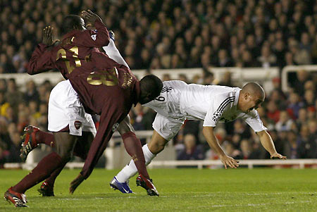 Real Madrid's Ronaldo (R) falls as he tries to evade the tackle of Arsenal's Emmanuel Eboue (L) and Kolo Toure (C) during their Champions League first knockout round second leg soccer match at Highbury, London March 8, 2006. [Reuters]