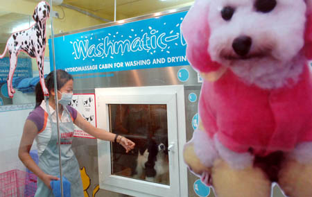 A pet dog is washed in a pet-bathing machine at a pet beauty center in Wuxi, a city of east China's Jiangsu Province, July 21, 2006. Pets can receive various services such as washing, drying, disinfecting and spraying fragrance in the machine introduced by the center. [Xinhua]