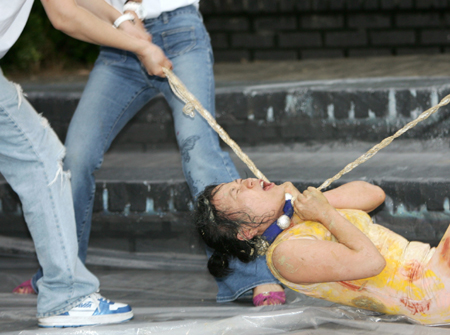 Models representing slaughtered dogs are laid on an altar during an art performance against eating dog meat in Seoul July 26, 2006. [Reuters]