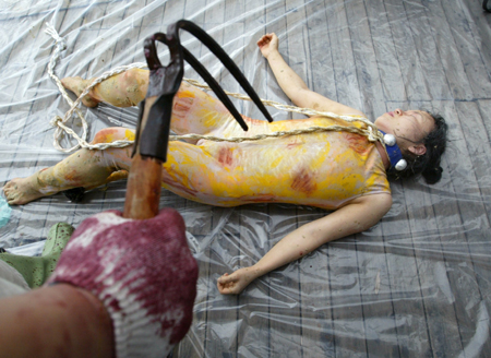 A performer playing the role of a dog waiting to be slaughtered, lies on the floor during an art performance against eating dog meat, in Seoul July 26, 2006. [Reuters]