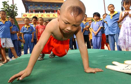 Lu Di, 6, does pushups as other young kungfu students watch at a kungfu school in Central China's Henan Province July 26, 2006. According to school president Shi Yongdi, Lu did 10,000 pushups in three hours and twenty minutes four days ago. Since he shows so much promise, Shi says the school will waive his tuition for ten years. [Xinhua]  