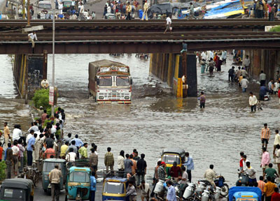 People move through a flooded road in Surat, about 260 km (162 miles) south of the western Indian city of Ahmedabad, August 8, 2006. Swirling floodwaters inundated several towns and cities in western and southern India on Tuesday as the military deployed helicopters and boats to help hundreds of thousands of marooned people. [Reuters]