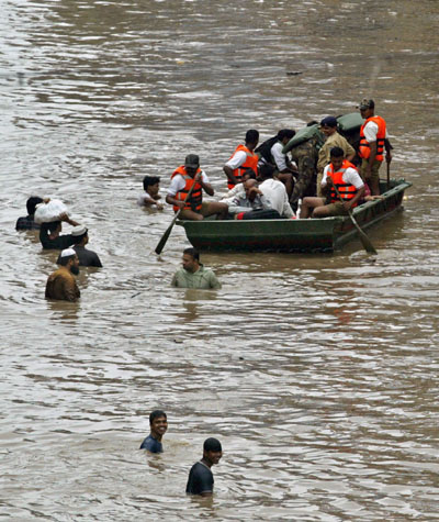 People move through a flooded road in Surat, about 260 km (162 miles) south of the western Indian city of Ahmedabad, August 8, 2006. Swirling floodwaters inundated several towns and cities in western and southern India on Tuesday as the military deployed helicopters and boats to help hundreds of thousands of marooned people.
