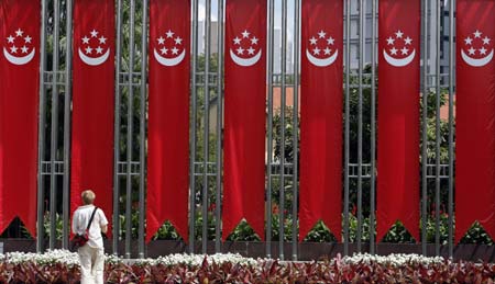 A man stands in front of a row of banners depicting Singapore's national symbol in Singapore August 8, 2006. 