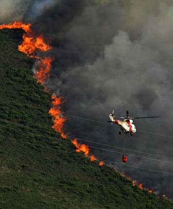 A car passes near a forest fire in Pardesoa, in the northwestern Spanish region of Galicia, August 11, 2006. [Reuters]
