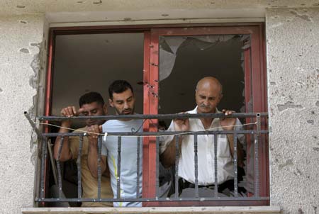 Residents examine the scene after a rocket hit a house in the northern Israeli town of Deir al-Assad August 10, 2006. A rocket fired by Lebanese Hizbollah guerrillas hit a house in Deir al-Assad on Thursday, killing two people, including a toddler, emergency services said. 