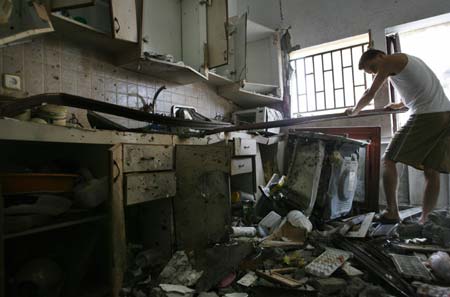 A resident examines the scene after a rocket hit a house in the northern Israeli town of Deir al-Assad August 10, 2006. A rocket fired by Lebanese Hizbollah guerrillas hit a house in Deir al-Assad on Thursday, killing two people, including a toddler, emergency services said. 
