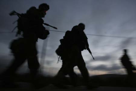 An Israeli soldier (L) smokes a cigarette at dawn as his unit returns from Lebanon near the northern town of Metula on the Israel-Lebanon border, August 12, 2006.