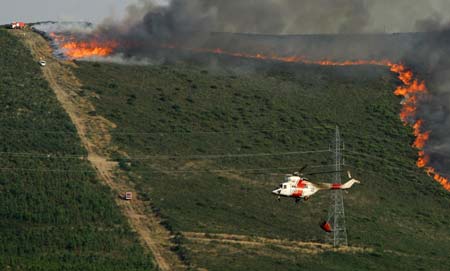 A helicopter flies over a forest fire in Pardesoa, in the northwestern Spanish region of Galicia, August 11, 2006. 