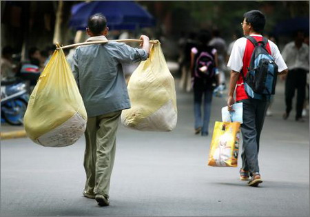 A man carrying the luggage walks with a freshman student in the campus of a university in Shanghai August 27 2006. Many parents accompanied their children to the university at the new term for college students. [Lu Haitao/Oriental Morning Post]