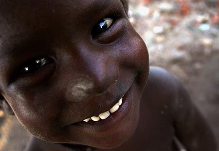 A boy smiles at the camera a demolished slum colony in New Delhi September 10, 2006.