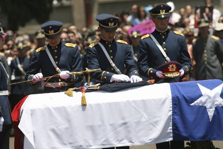 Chilean Army cadets remove the uniform, sable and hat from the coffin of former Chilean dictator Augusto Pinochet, at the end of his funeral mass in the courtyard of the Military College in Santiago, December 12, 2006. 